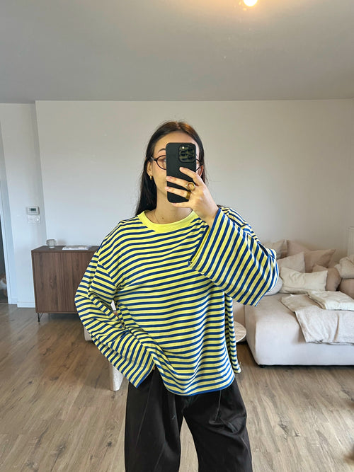 Top Dounia Oversize rayé bleu roi et jaune, coupe ample et manches longues, porté avec pantalon fluide pour un look tendance et facile à associer.