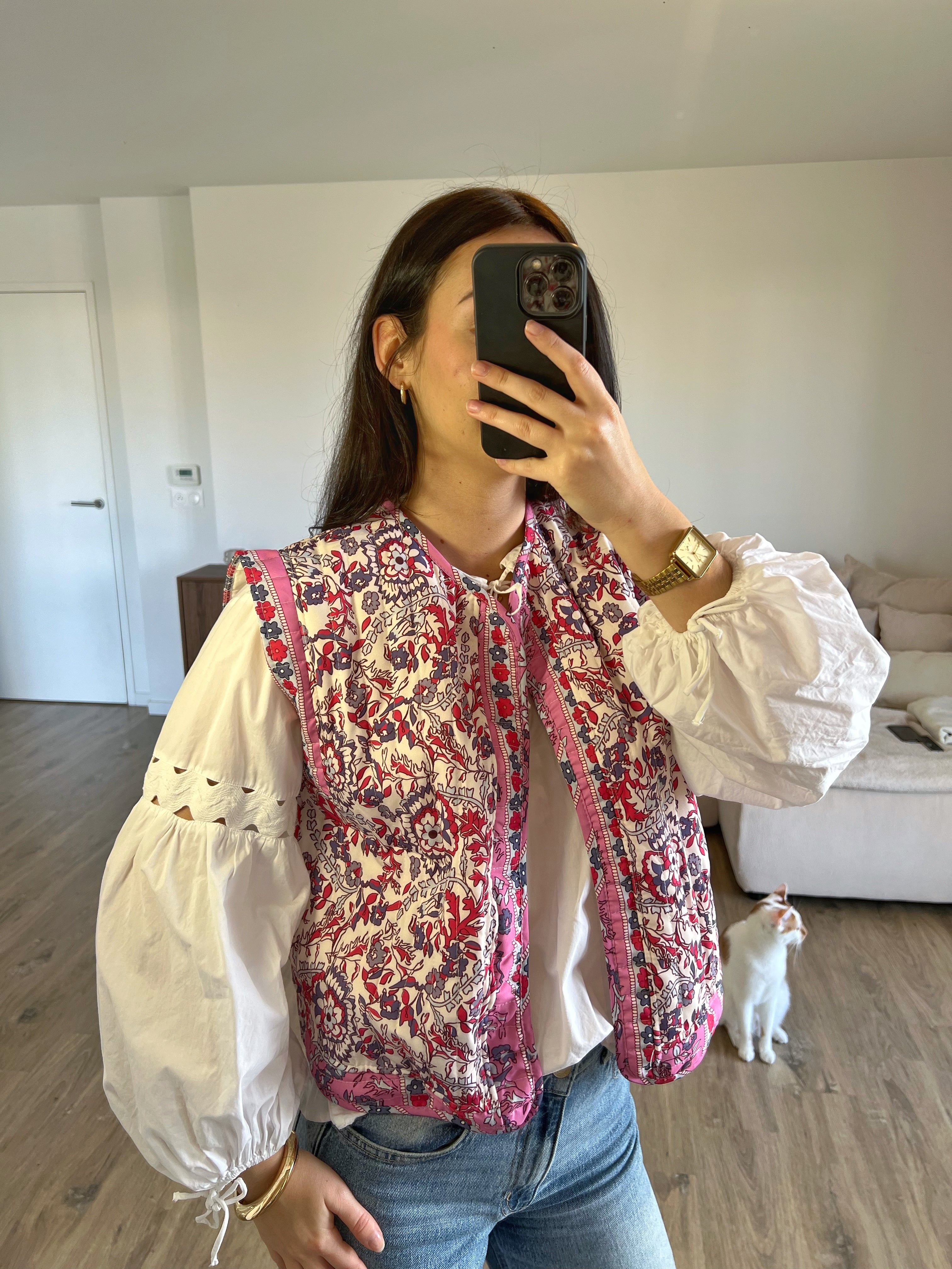 Veste sans manches fleurie rose portée avec une blouse blanche, look printanier