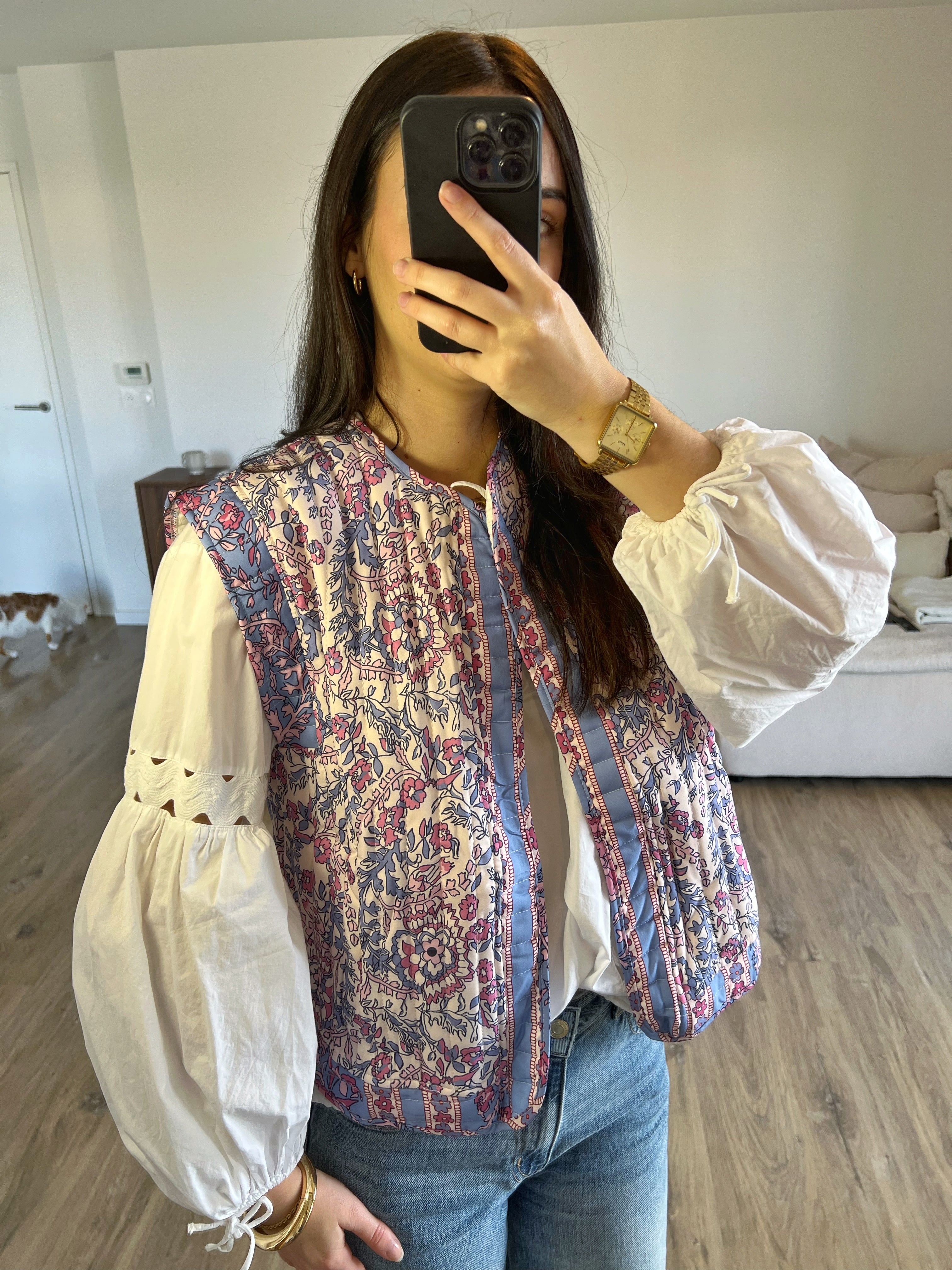 Veste sans manches fleurie violet pastel portée avec une blouse blanche